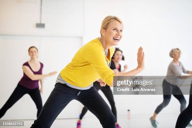 mature woman enjoying dancing at fitness studio - zumba class stock-fotos und bilder