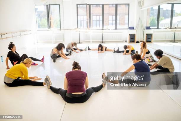 multiracial women doing stretching workout in fitness club - legs apart imagens e fotografias de stock