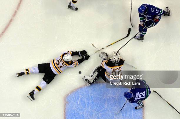 Tim Thomas of the Boston Bruins makes a save against Raffi Torres and Maxim Lapierre of the Vancouver Canucks as Andrew Ference falls to the ice...