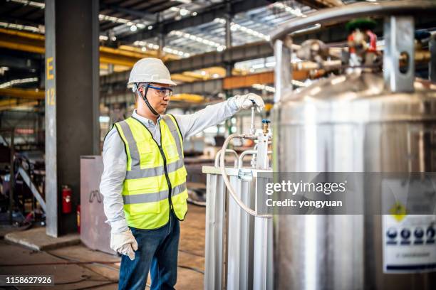 operaio asiatico che gestisce un serbatoio del gas in una fabbrica - valvola di sfiato foto e immagini stock