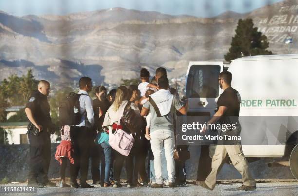 As seen through fencing, migrants enter a Border Patrol vehicle while being detained, after crossing to the U.S. Side of the U.S.-Mexico border...