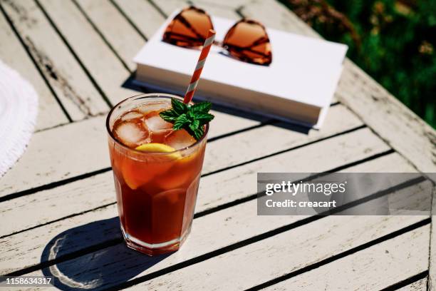 sommer-szene, eistee mit zitrone und minze auf einem gartentisch bei strahlendem sonnenschein. - ice tea stock-fotos und bilder