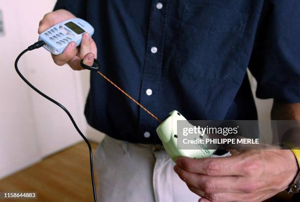 Une personne recharge sa batterie de téléphone portable grâce à un chargeur autonome actionné à la main "La Souris verte", le 2 juillet 2002 à Lyon....