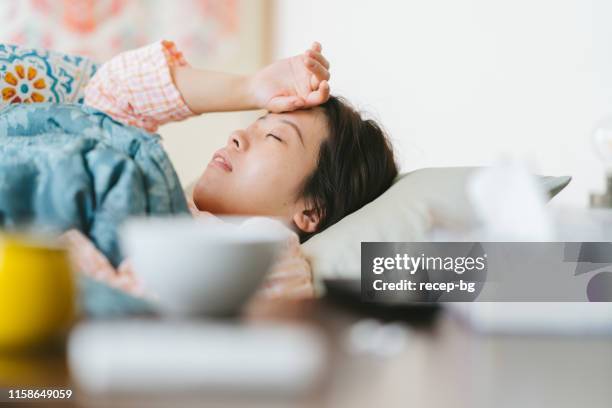 frauen fühlen sich krank und schlafen auf dem sofa zu hause - grippevirus stock-fotos und bilder