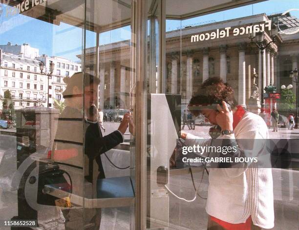 Deux personnes téléphonent, le 22 septembre, dans les cabines de France-Télécom installées devant la Bourse des valeurs à Paris. Le ministère des...