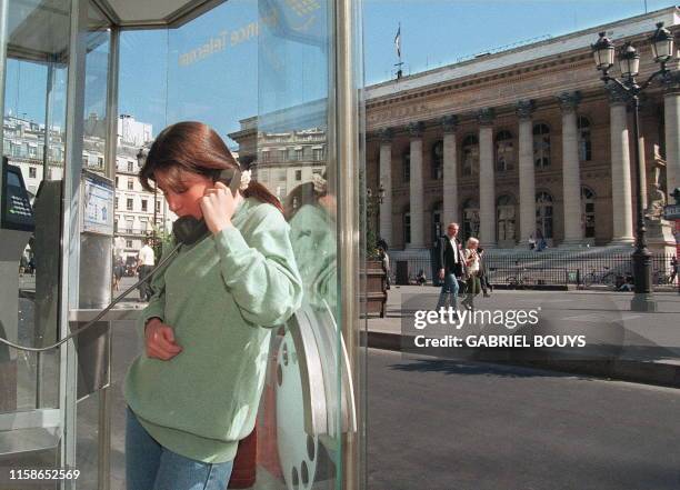 Une jeune fille téléphone, le 22 septembre, dans une cabine de France-Télécom installée devant la Bourse des valeurs à Paris. Le ministère des...