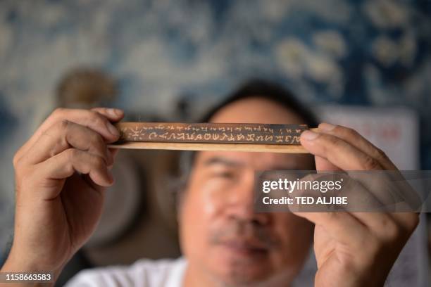 This photo taken on June 11, 2019 shows cultural advocate Leo Emmanuel Castro holding a piece of bamboo inscribed with indigenous Baybayin script at...