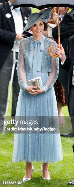 Catherine, Duchess of Cambridge shelters under an umbrella as she attends day one of Royal Ascot at Ascot Racecourse on June 18, 2019 in Ascot,...