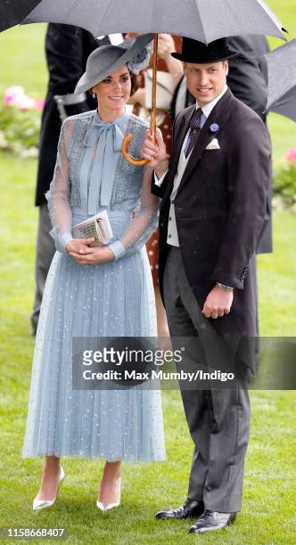 Catherine, Duchess of Cambridge and Prince William, Duke of Cambridge shelter under an umbrella as they attend day one of Royal Ascot at Ascot...
