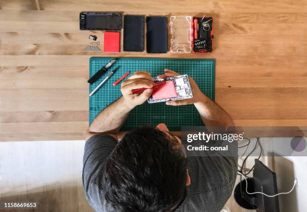 smart phone repairing man with screwdriver - repairing imagens e fotografias de stock