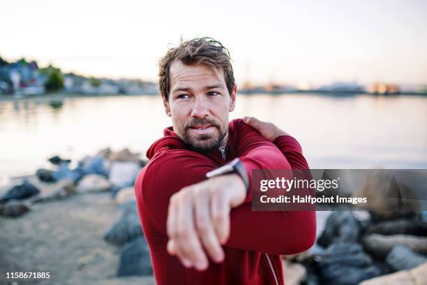 a fit mature sportsman runner doing exercise outdoors on beach, stretching. - actieve levenswijze stockfoto's en -beelden