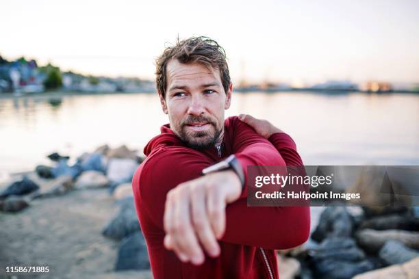 a fit mature sportsman runner doing exercise outdoors on beach, stretching. - men's health bildbanksfoton och bilder