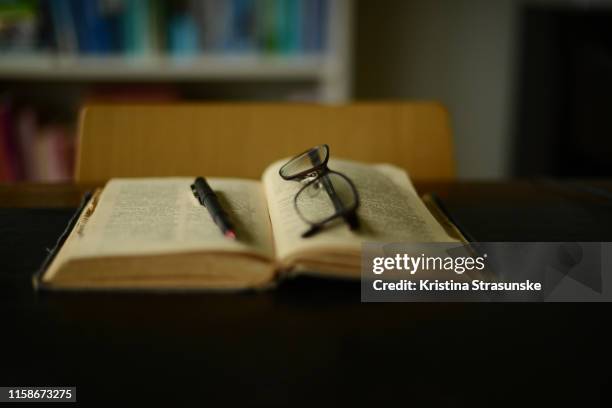 reading glasses and a pen on an old vintage dictionary - occhiali da lettura foto e immagini stock