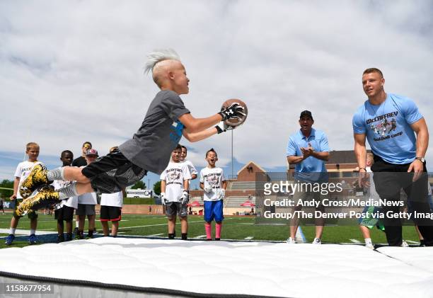 Hudson Larose launches in the air to catch the football tossed by Carolina Panthers RB Christian McCaffrey during the McCaffrey Football Camp at...