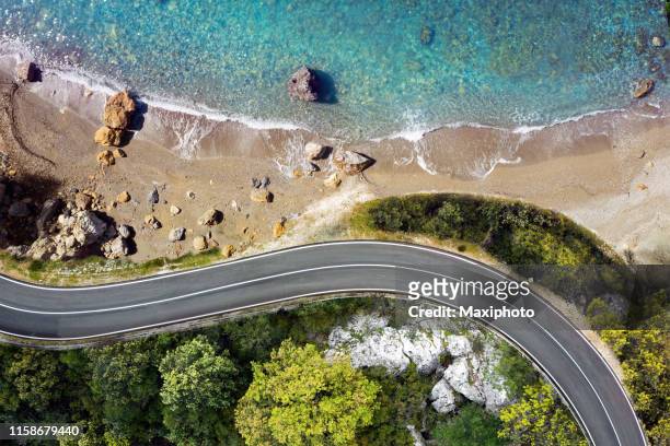 strada sul mare che si avvicina a una spiaggia, vista dall'alto - autostrada foto e immagini stock