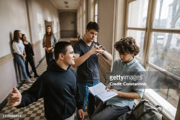 boys bullying classmate in the school corridor while girls watching - incidental people stock pictures, royalty-free photos & images