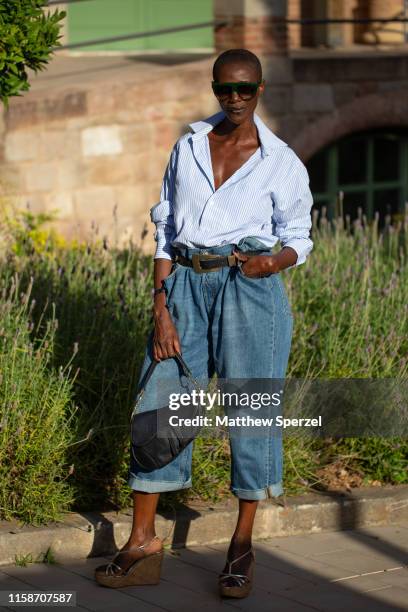 Guest is seen on the street attending 080 Barcelona Fashion Week wearing blue shirt, high-waisted blue jeans, black belt and black Dior bag on June...