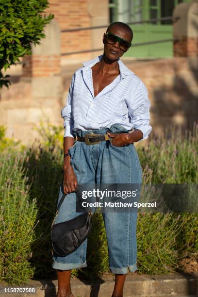 Guest is seen on the street attending 080 Barcelona Fashion Week wearing blue shirt, high-waisted blue jeans, black belt and black Dior bag on June...