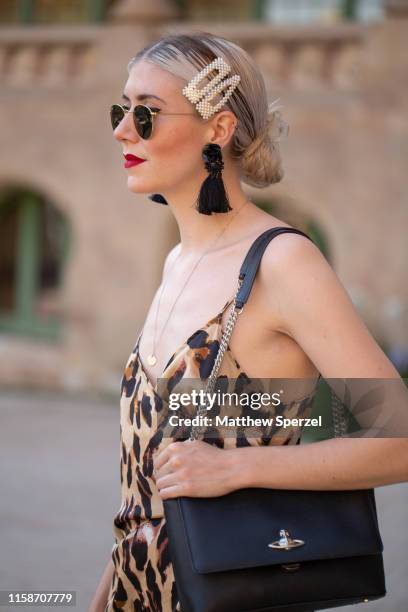 Guest is seen on the street attending 080 Barcelona Fashion Week wearing leopard print dress, black Vivienne Westwood bag, pearl barrettes, black...