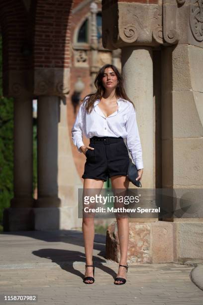 Guest is seen on the street attending 080 Barcelona Fashion Week wearing white button-down shirt with black shorts and strappy black sandals on June...