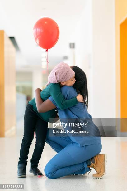 el doctor le da un globo rojo a una niña con cáncer - enfermedad crónica fotografías e imágenes de stock