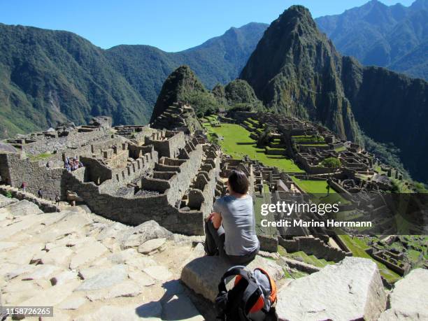 woman sitting on a rock sighting machu picchu from above - sabbatical stockfoto's en -beelden