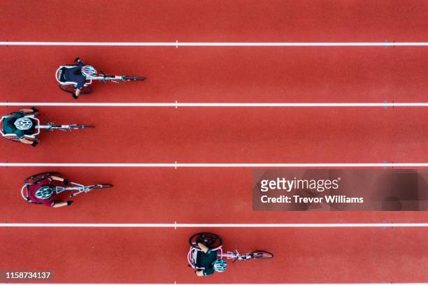 view from directly above four women racing in wheelchairs - match sport photos et images de collection