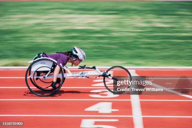 young female wheelchair racers crossing the finish line at a track and field event - frau rollstuhl selbstständigkeit stock-fotos und bilder