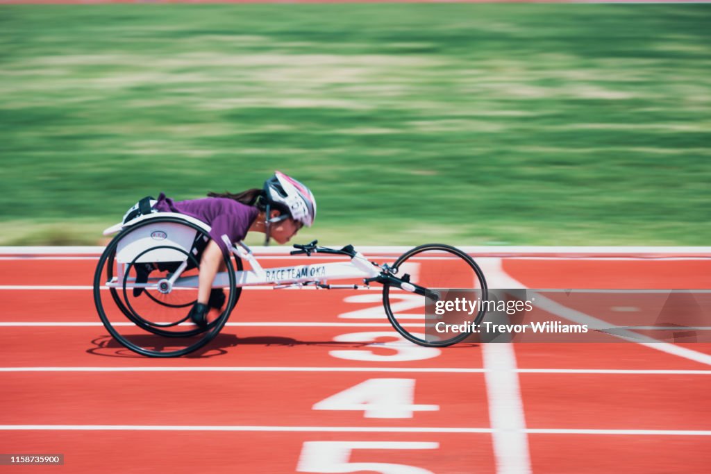 Young female wheelchair racers crossing the finish line at a track and field event