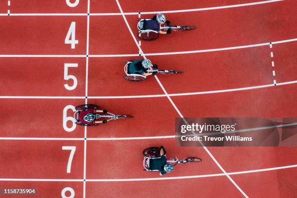 view from directly above four women racing in wheelchairs crossing the finish line - sportler mit behinderung stock-fotos und bilder