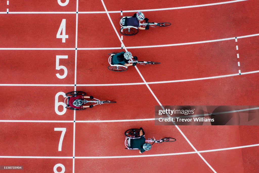 View from directly above four women racing in wheelchairs crossing the finish line