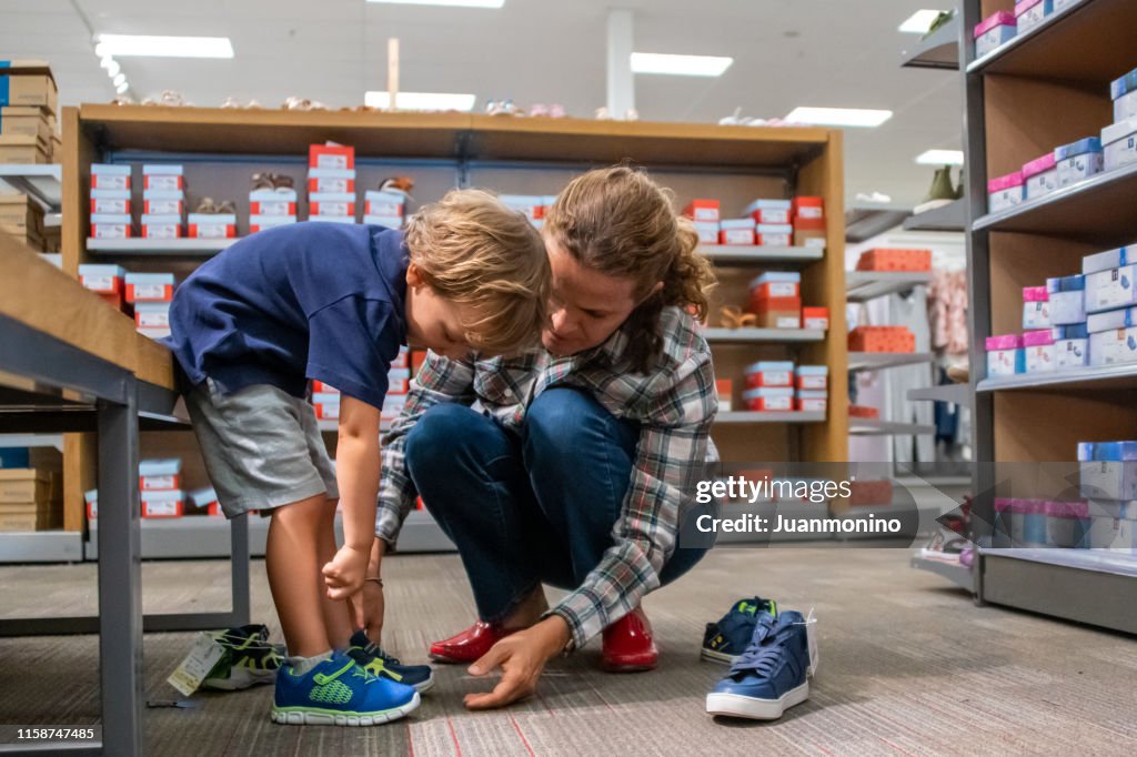 Mujer madura comprando zapatos para su hijo