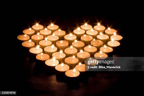 lighted candles making a heart shape - kaarsen stockfoto's en -beelden
