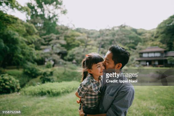 japanese father kissing preschool mixed race daughter - mixed race family stock-fotos und bilder