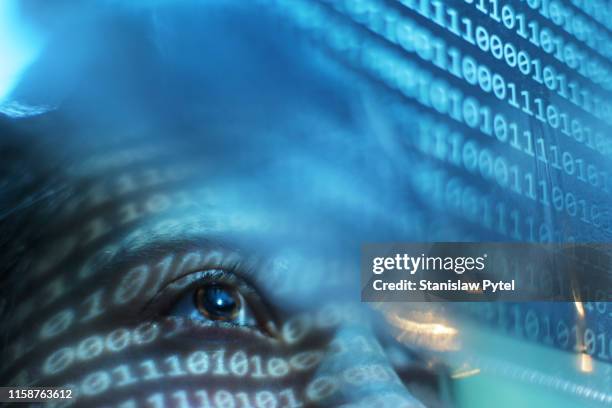 portrait of woman looking on blue screen lit with binary code - one number stock-fotos und bilder