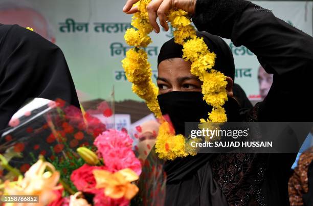 Muslim woman holds a garland of flowers to celebrate the passage of a law to outlaw Triple Talaq, or "instant divorce," at an event organised by the...