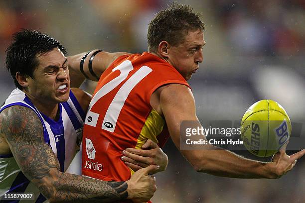 Daniel Harris of the Suns is tackled by Aaron Edwards of the Kangaroos during the round 12 AFL match between the Gold Coast Suns and the North...