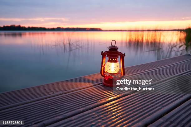 still life of lantern standing on a jetty at an idyllic lake during sunset - lantern stock pictures, royalty-free photos & images