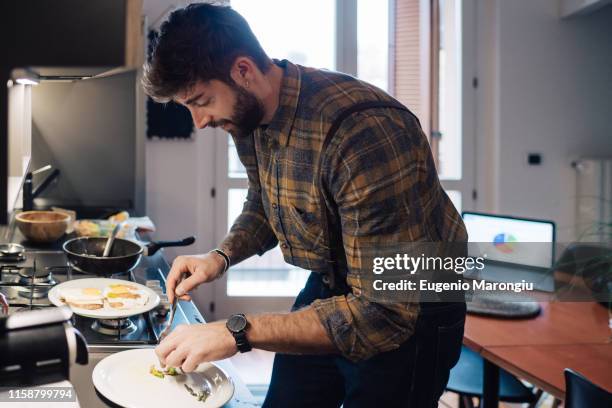 mid adult man plating food at kitchen counter - food plating stock-fotos und bilder