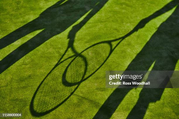 cropped shadows of two tennis players with tennis rackets on green lawn - racchetta da tennis foto e immagini stock