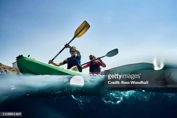teenage boy and mother sea kayaking on ocean, surface level view, limnos, khios, greece - sea kayaking imagens e fotografias de stock