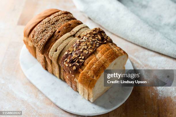 sliced loaf made up of variety of white and wholemeal slices on cutting board, high angle view - vollkornbrot stock-fotos und bilder