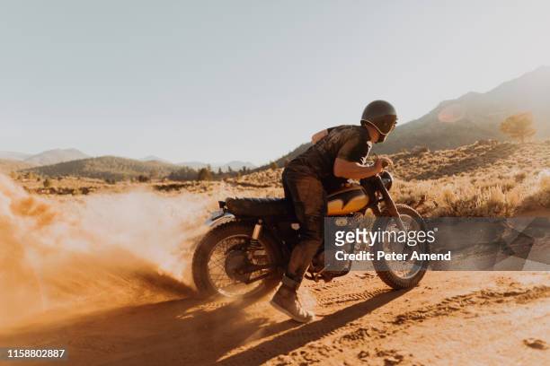 motorbiker raising dust, kennedy meadows, california, us - dirt road motorbike stock-fotos und bilder