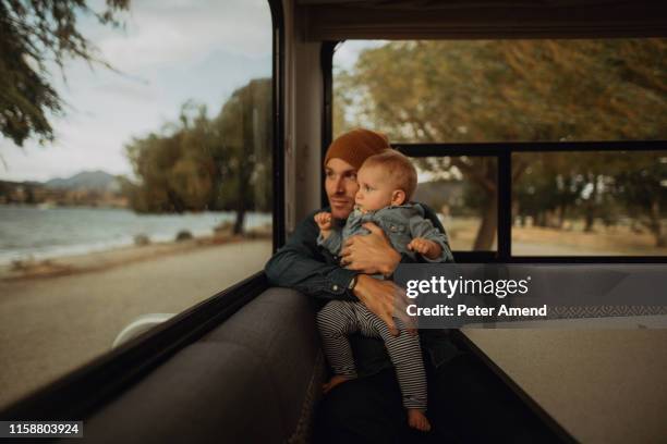 father and baby looking out window of motorhome, wanaka, taranaki, new zealand - family new zealand stockfoto's en -beelden