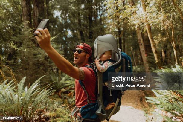 father with baby taking selfie in forest, queenstown, canterbury, new zealand - portabebés fotografías e imágenes de stock