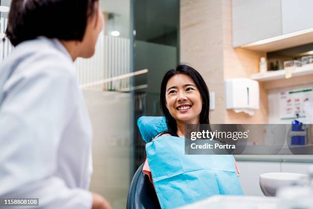 smiling patient looking at dentist in clinic - dentist office stock pictures, royalty-free photos & images