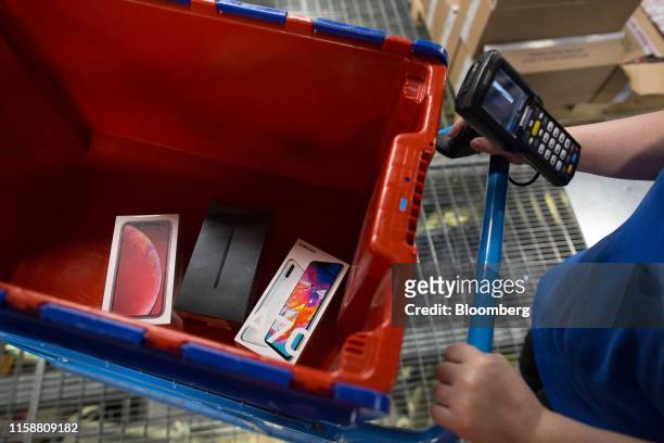 Worker picks an order including a Samsung Electronics Co. A70 smartphone and an Apple Inc. IPhone XR smartphone at the Ozon.ru fulfillment center in...