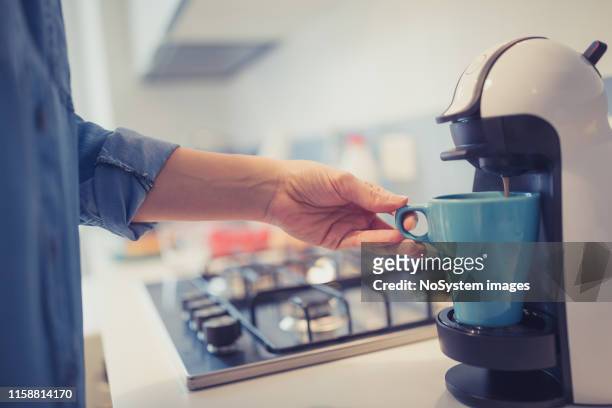 jonge vrouw maakt 's ochtends koffie in haar keuken. - coffee machine stockfoto's en -beelden