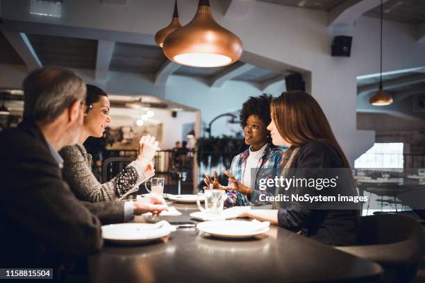 senior businessman and his two female colleagues having business meeting in restaurant. - business lunch stock pictures, royalty-free photos & images