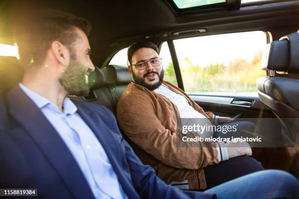 two men sitting on back seat in car and talking - man sitting inside car stock pictures, royalty-free photos & images